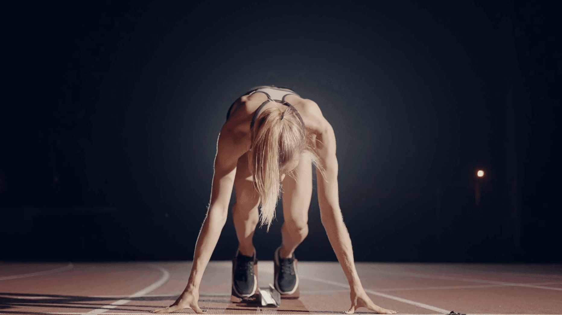 Sprinter set in the starting blocks under stadium lights
